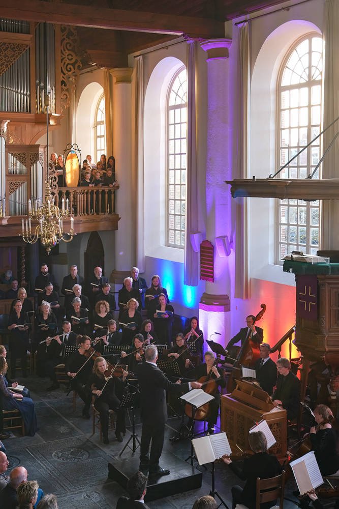 De Hobbe van Baerdtkerk tijdens de uitvoering, met het orgel en de kroonluchter boven het koor en orkest.