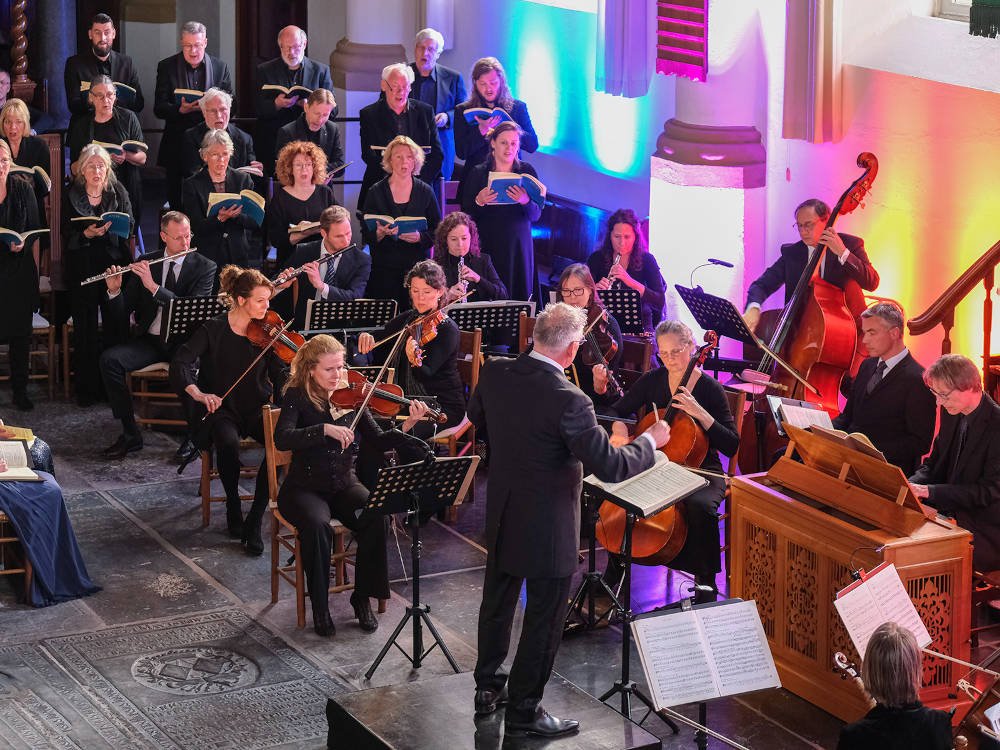 Het orkest met dirigent Jan Vermaning op de rug gezien, het kistorgel rechts en de contrabas achterin.